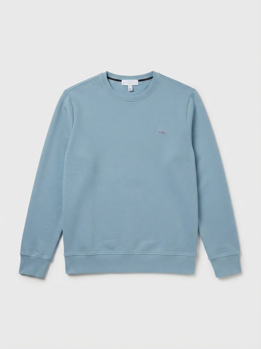 Le même sweat bleu-gris, à plat sur une surface neutre claire, cadré en portrait.